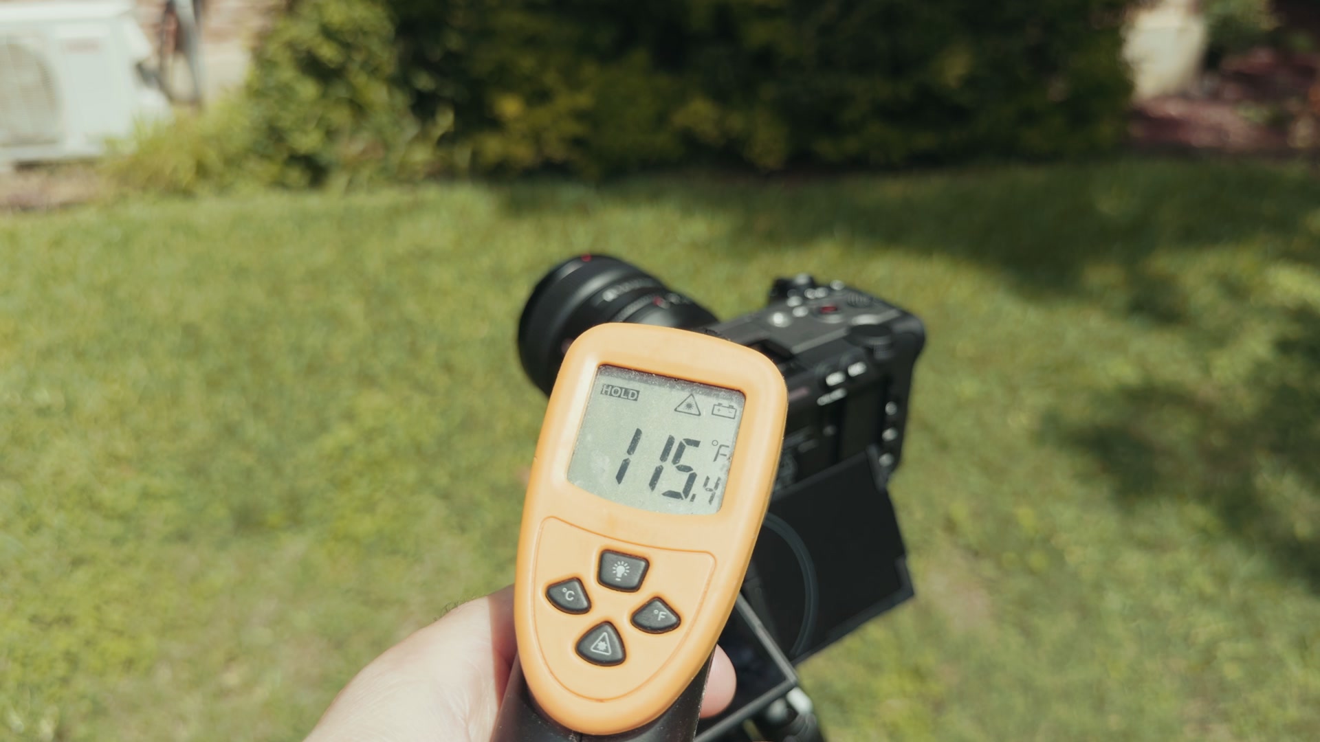An infrared thermometer reading 115.4 degrees Fahrenheit held in front of the Sony FX5 recording outdoors on a tripod
