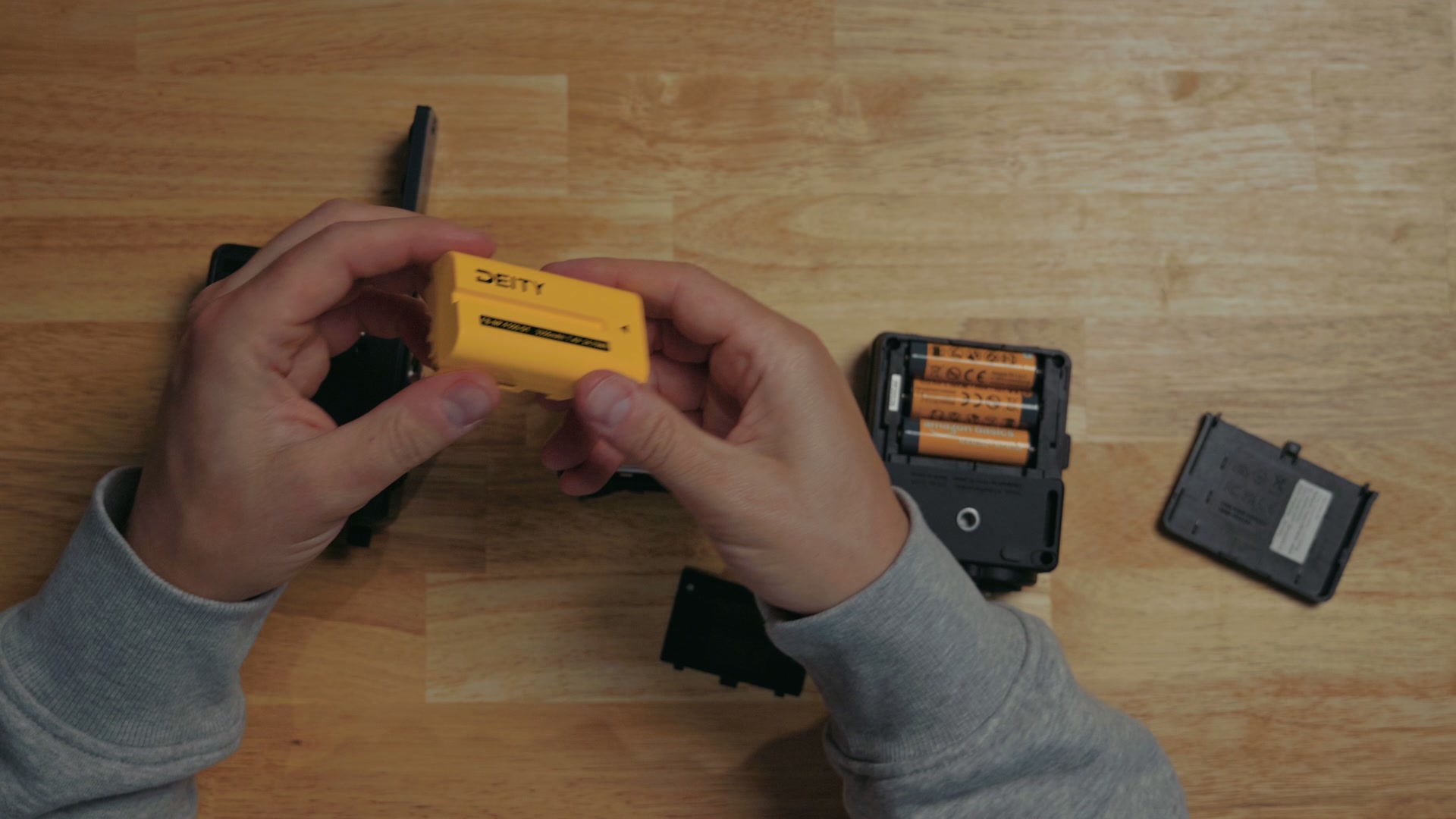 An NP-F550 rechargeable battery next to the AA batteries used by the Zoom F3 and Tascam FR-AV2