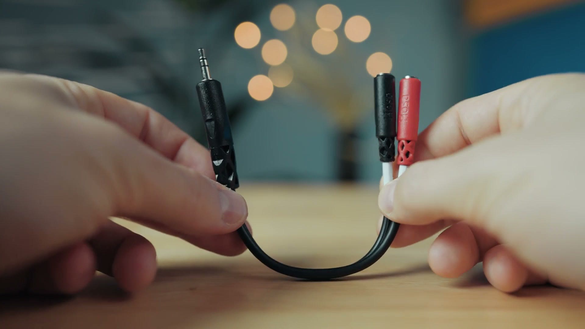 A 3.5mm audio splitter cable held in one hand