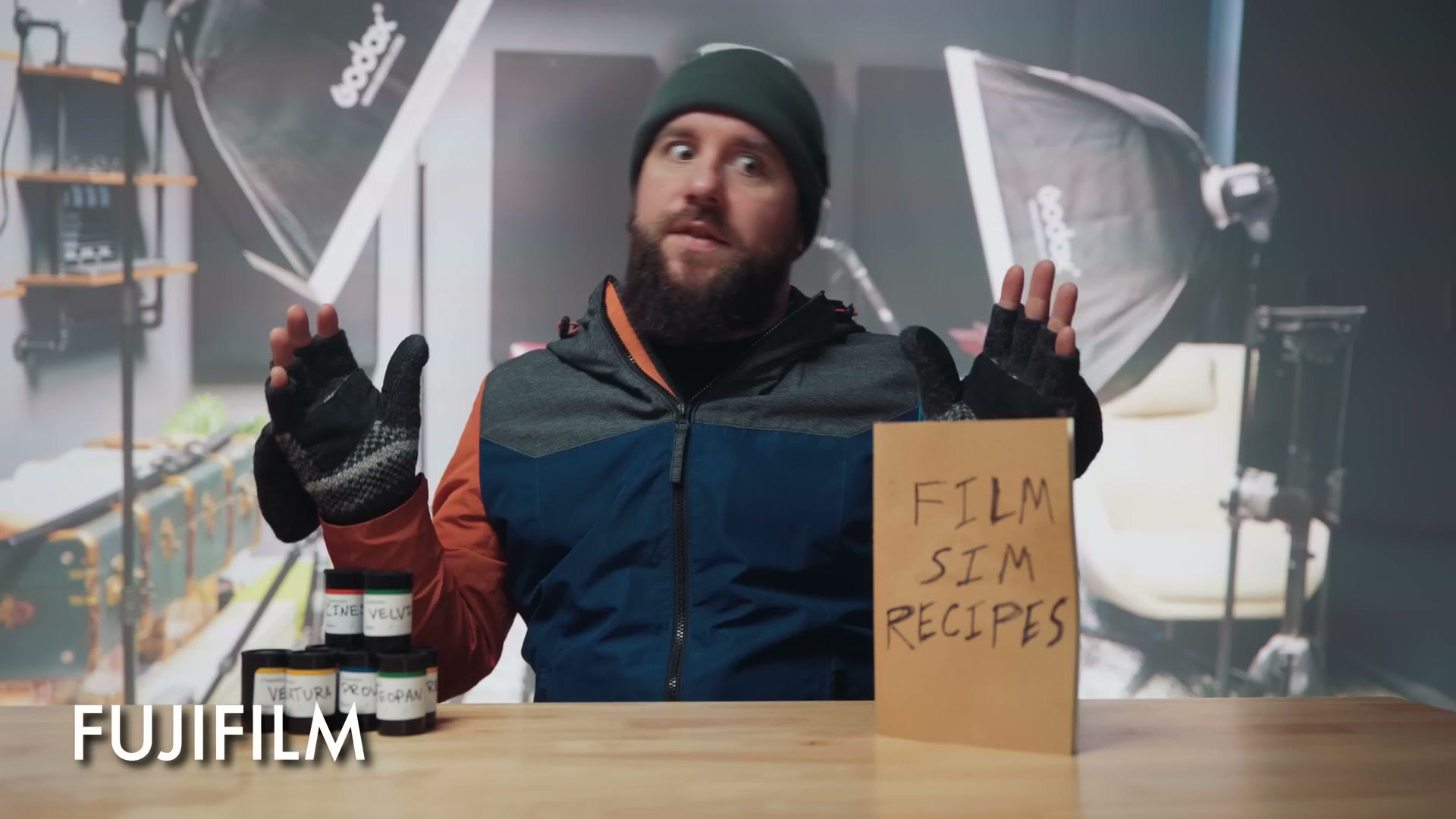 Matt dressed as Fujifilm in a beanie and fingerless gloves, with film canisters and a handwritten sign reading Film Sim Recipes