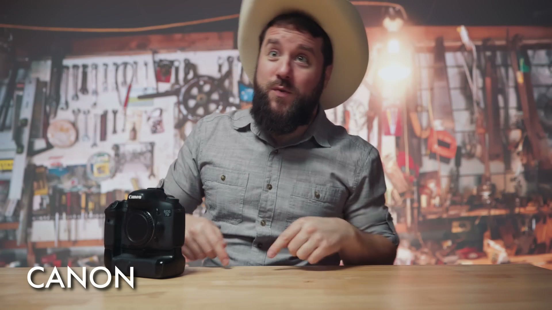 Matt dressed as Canon in a cowboy hat in a workshop, with a Canon DSLR and battery grip on the desk
