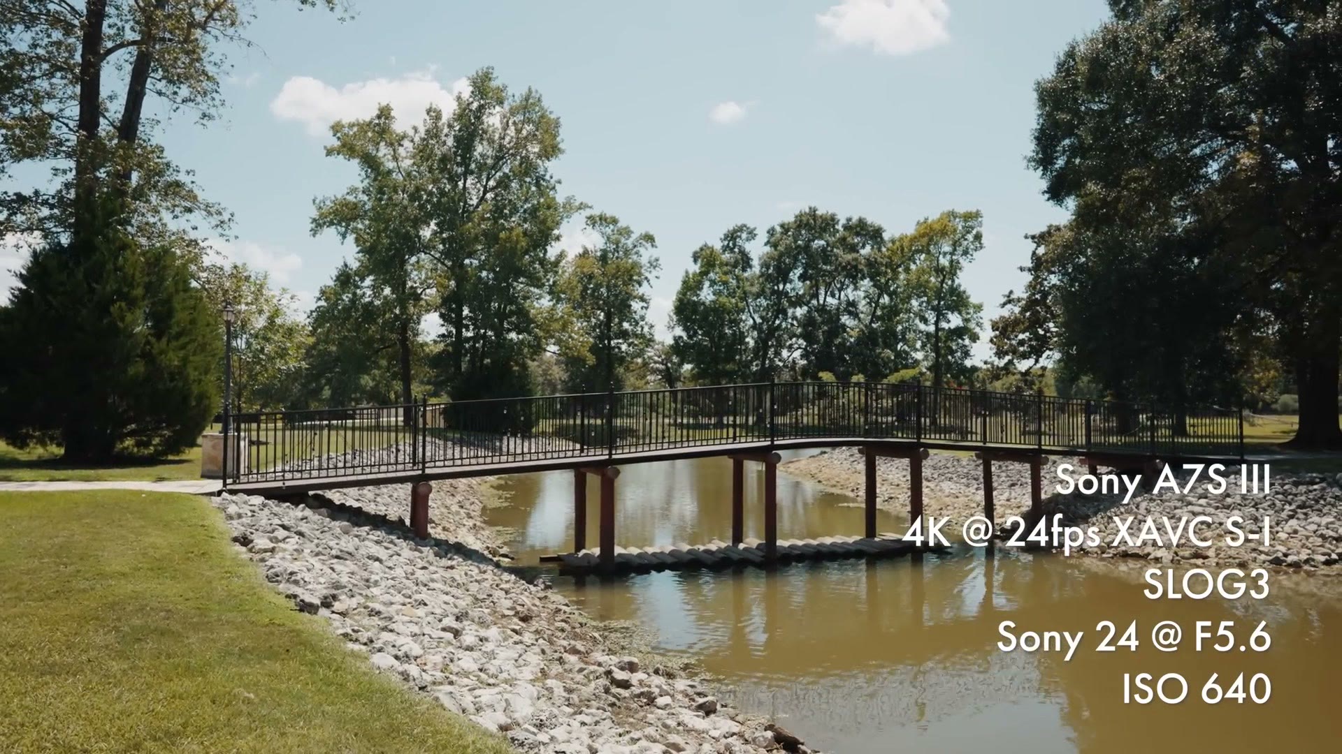 A wide shot of a wooden footbridge over a creek, overlaid with the text Sony A7S III, 4K at 24fps XAVC S-I, SLOG3, ISO 640.
