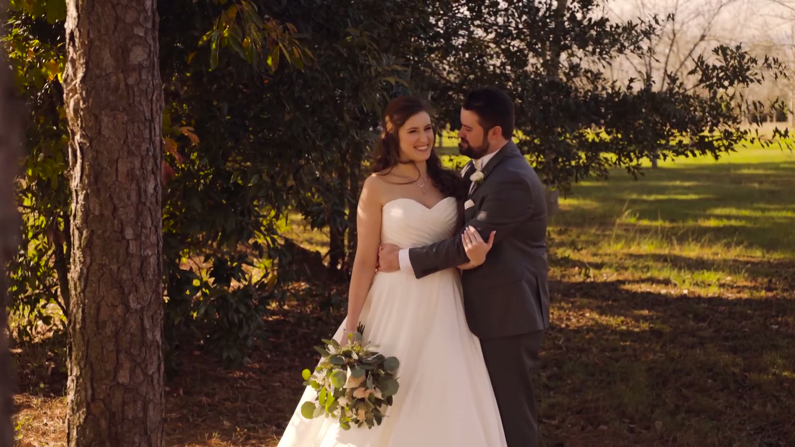 Finished color-graded frame of the bride and groom smiling among trees in warm golden-hour light, no editing interface visible