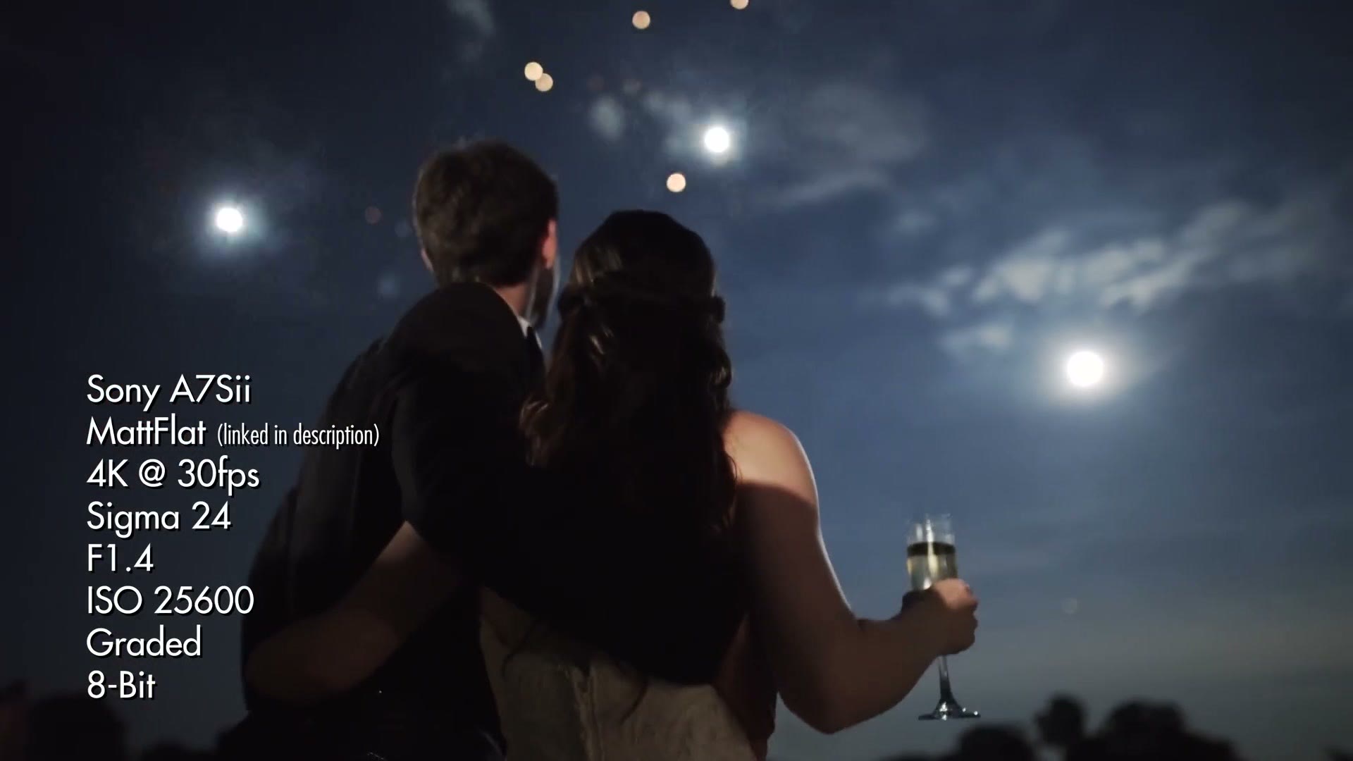 Couple watching fireworks under a full moon, overlaid with settings reading Sony A7Sii, MattFlat, 4K at 30fps, Sigma 24, F1.4, ISO 25600