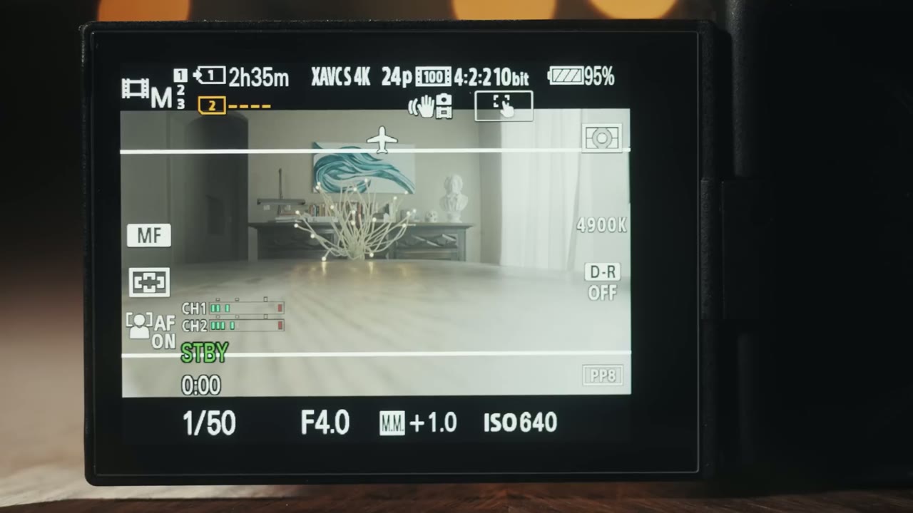 Same living room framed with thin white 2.35:1 aspect ratio guide lines and camera in STBY, not recording