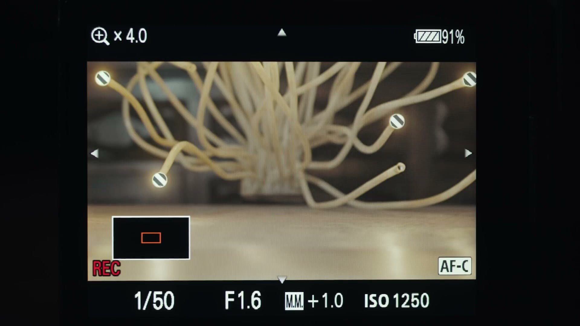 A Sony a7S III rear screen punched in 4x while recording, showing a sharp magnified image at 1/50, F1.6, ISO 1250