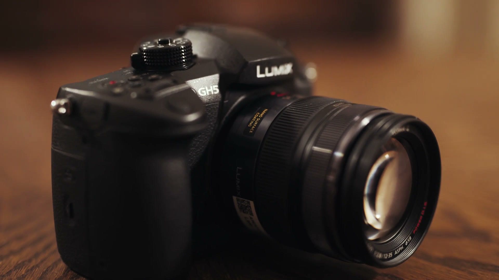Panasonic Lumix GH5 with a lens attached, sitting on a wooden table class=