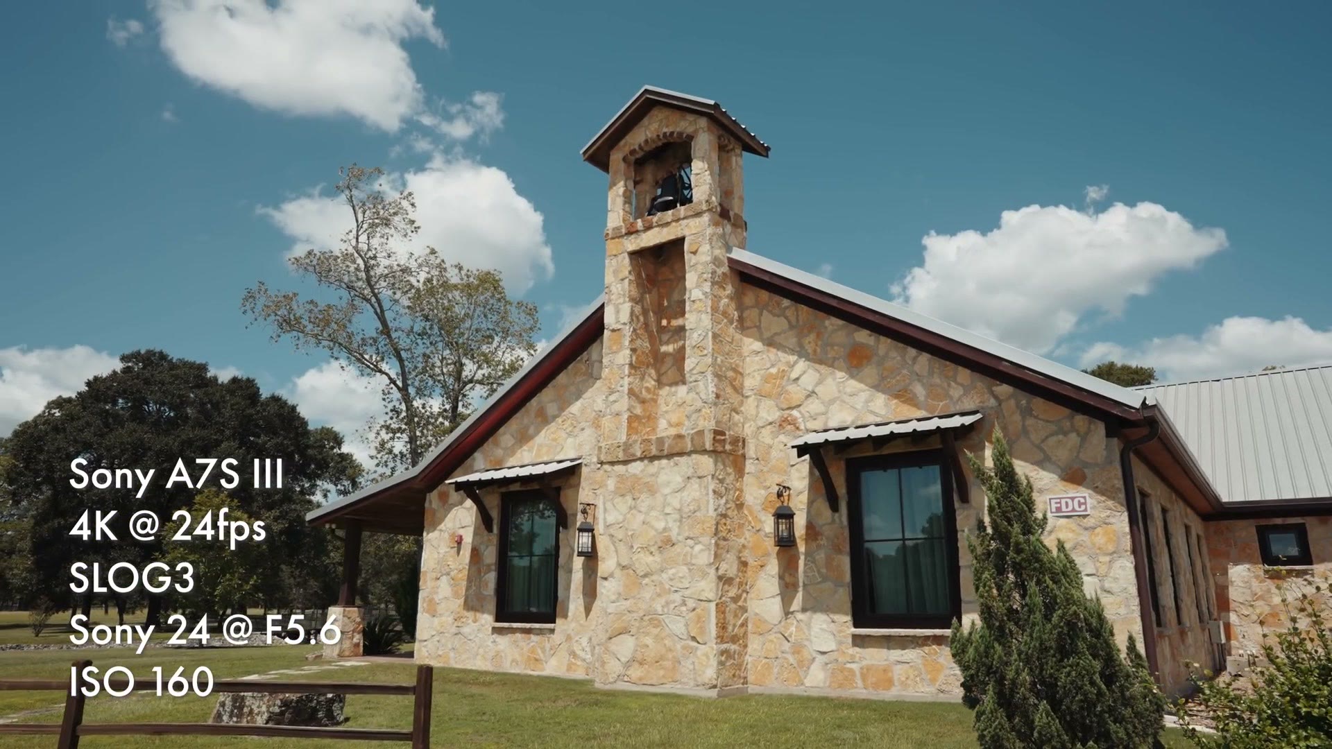 A stone chapel photographed against a bright blue sky with white clouds, with an overlay reading Sony A7S III, 4K at 24fps, SLOG3, Sony 24 at F5.6, ISO 160
