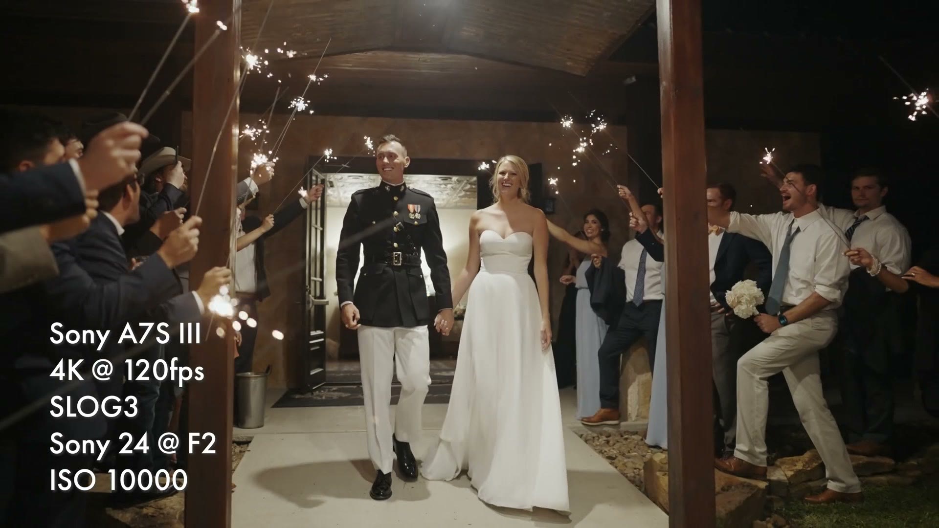 A bride and groom walking hand in hand through a tunnel of guests holding sparklers at night, overlay reading 4K at 120fps, SLOG3, ISO 10000