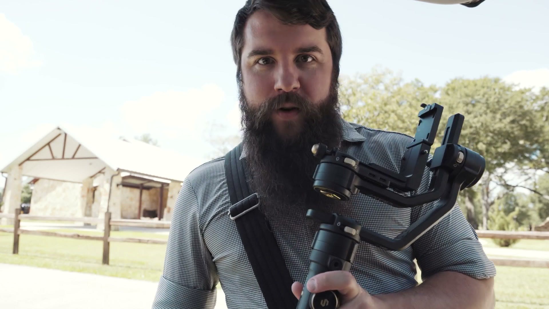 Matt holding an unloaded Zhiyun Crane 2S gimbal outside a stone wedding venue
