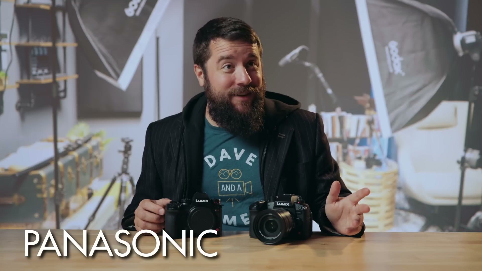 Matt in a black jacket with two Lumix bodies on the table in front of him, captioned PANASONIC