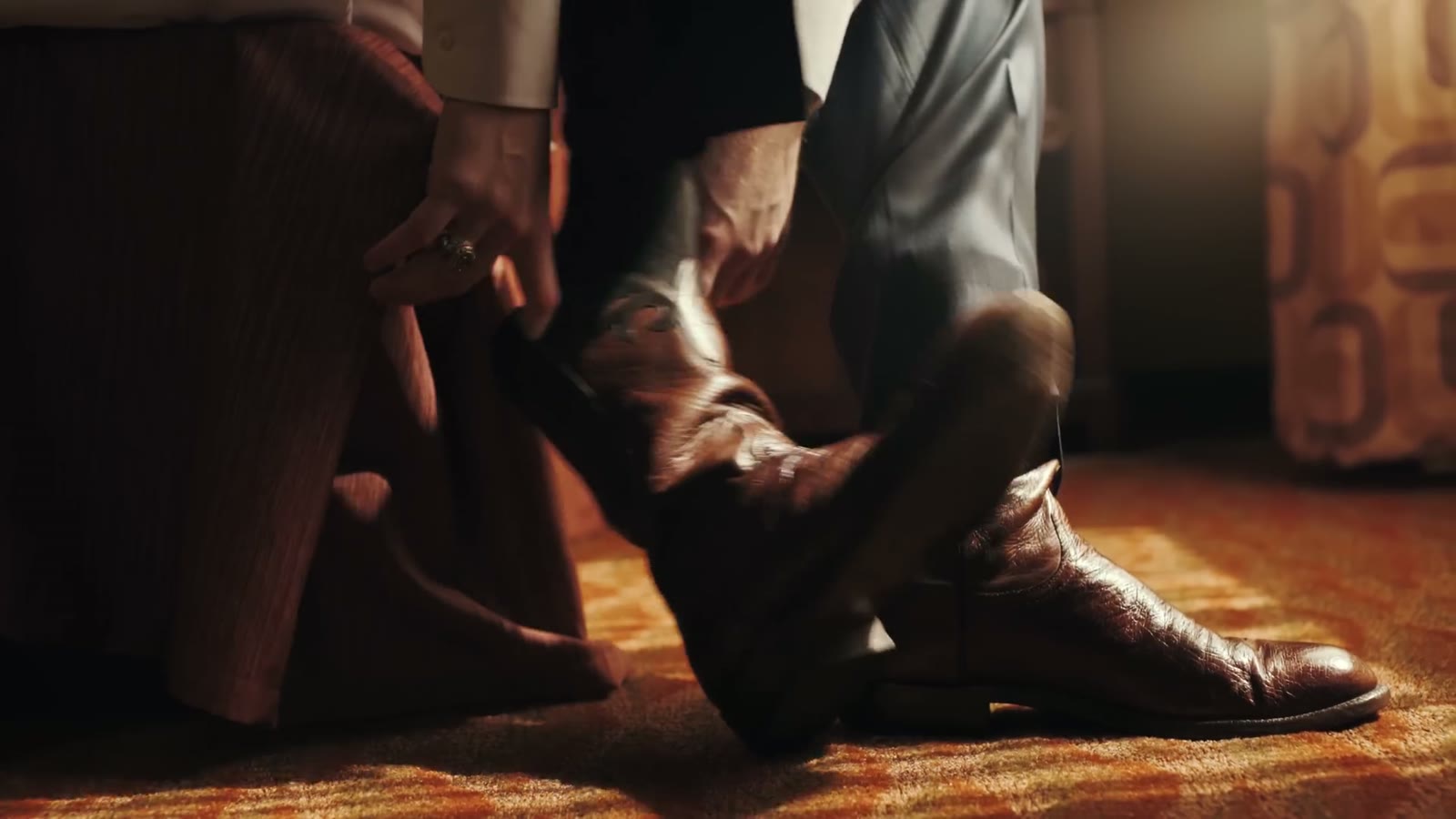 Close-up of the groom's feet as he pulls on brown leather boots
