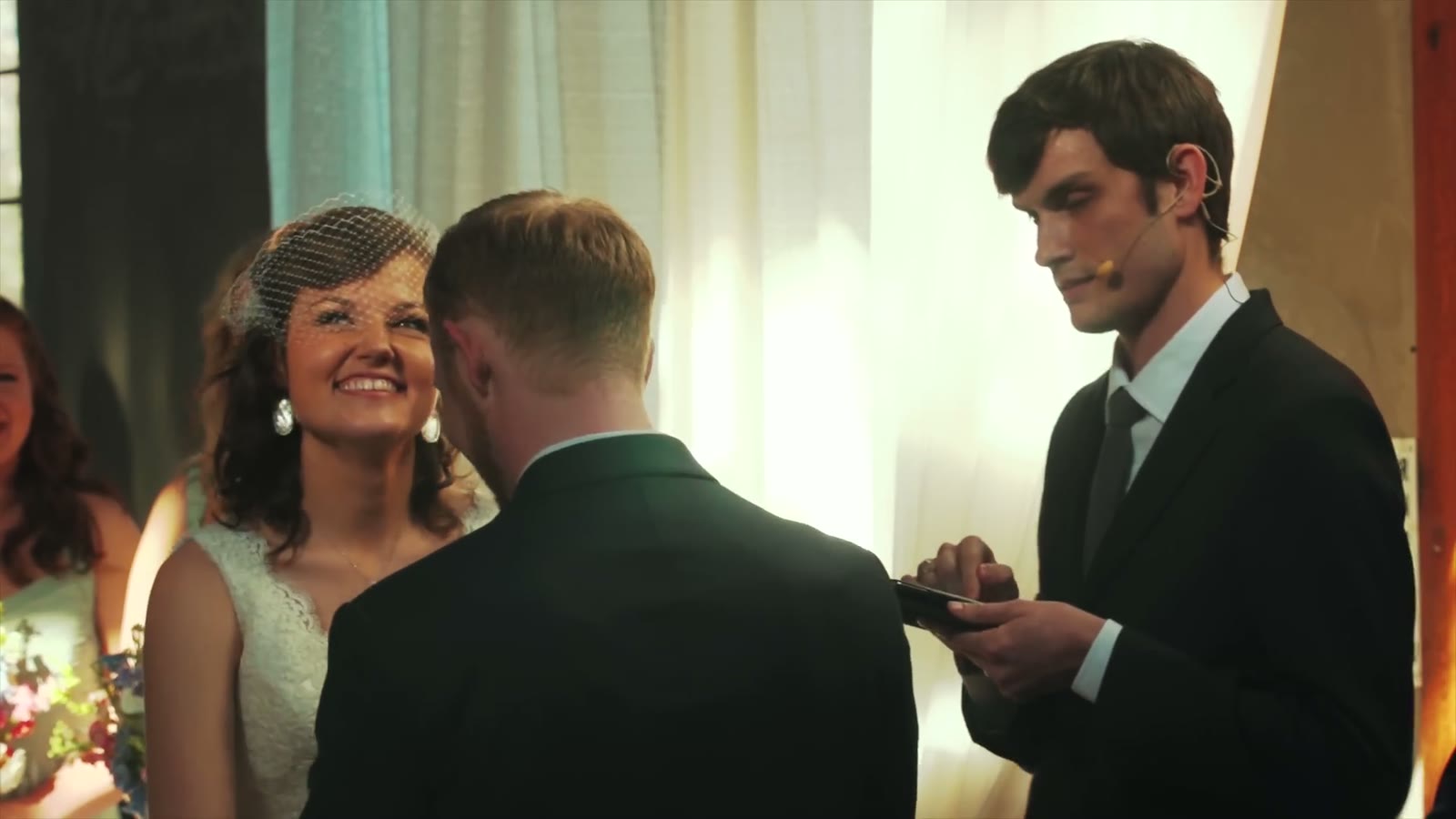 Officiant reading vows from his phone while the groom listens and the bride smiles
