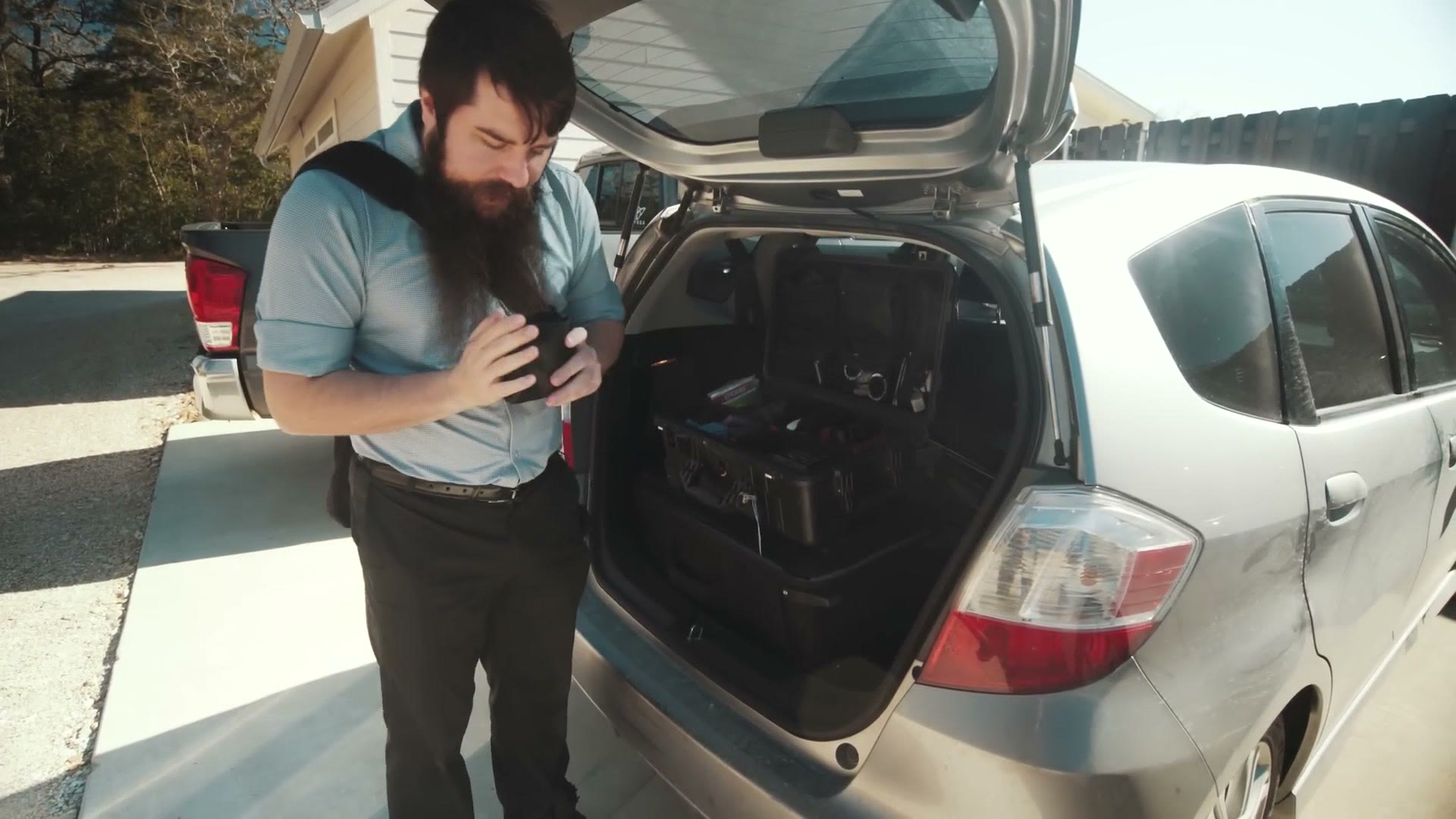 Matt holding a white Tascam DR-10L recorder beside his car.