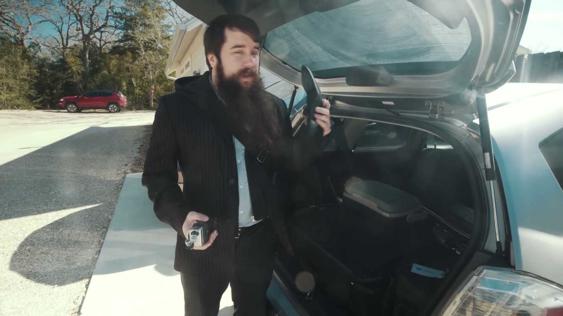 Matt standing at the open boot of his car holding a Zoom H5 audio recorder.