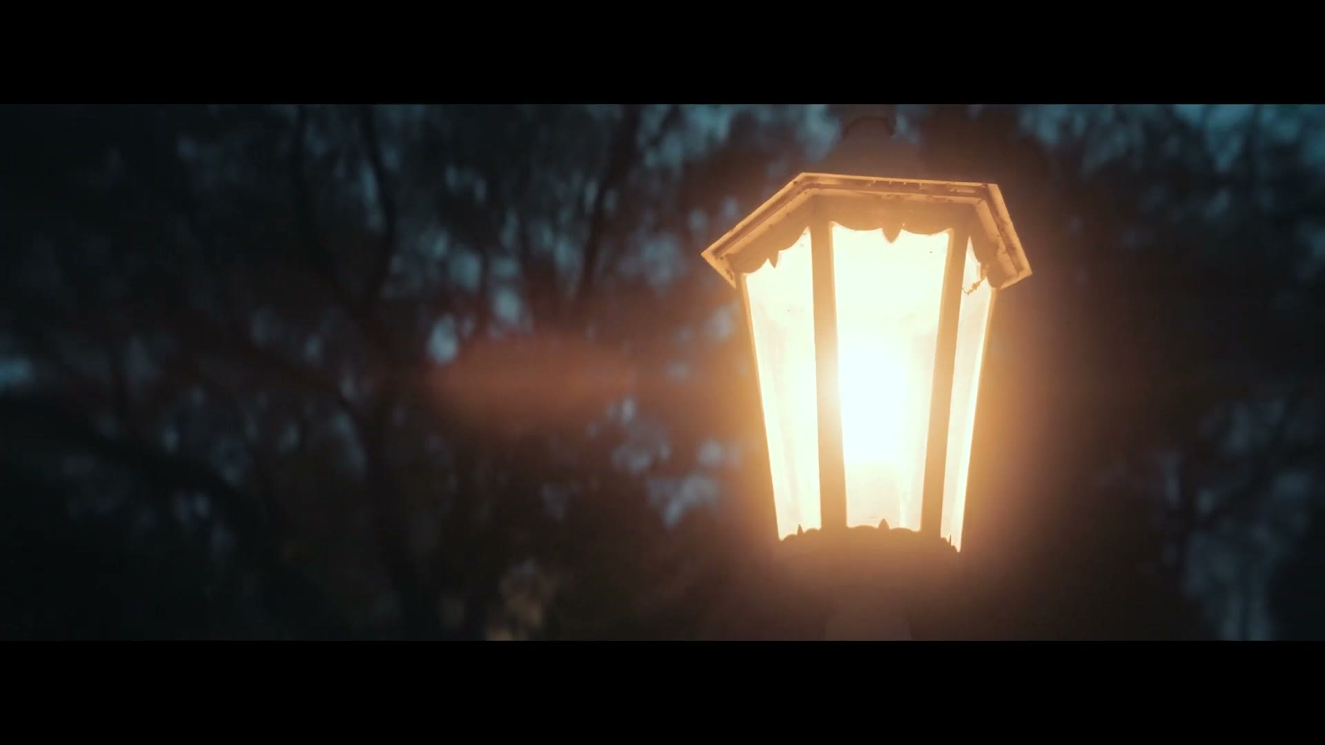 Warm orange flare streaking across a lantern at dusk, filmed with the neutral flare version of the Sirui lens
