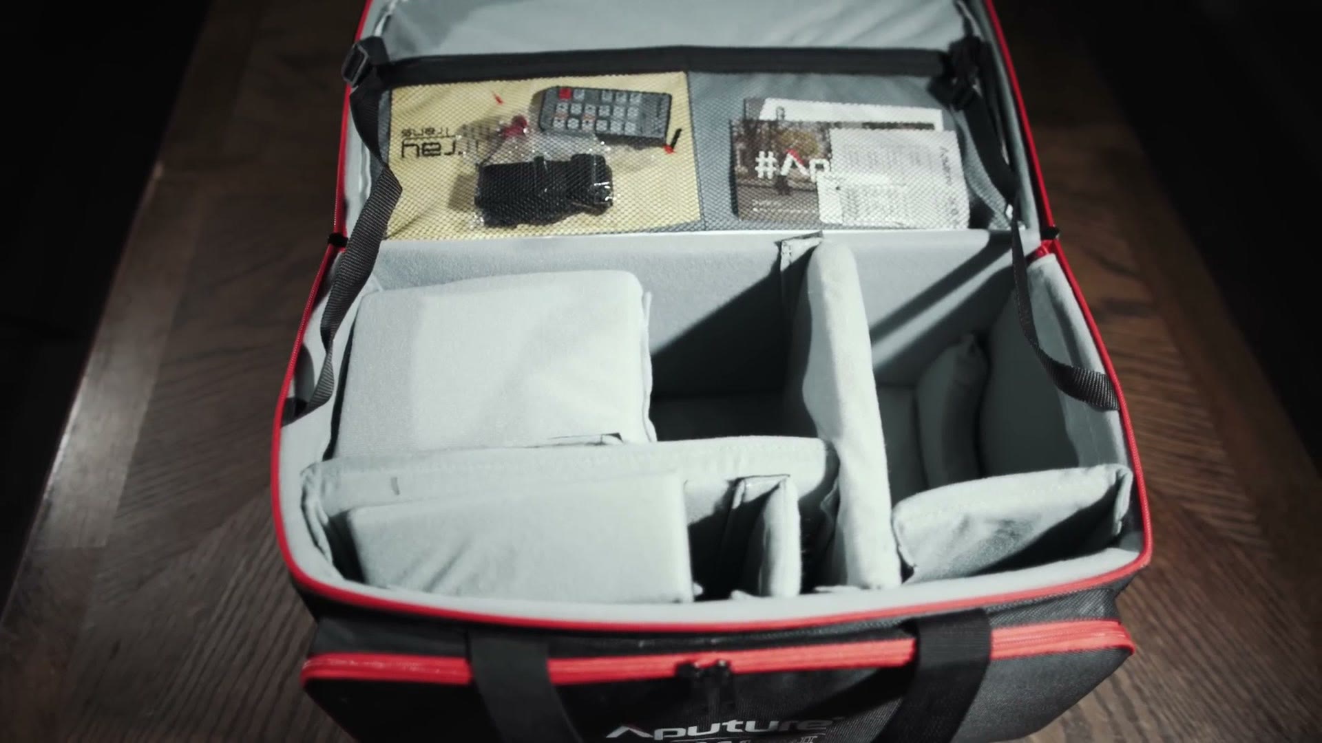 The open Aputure LS C 120d II hard-sided carry bag on a table, with padded dividers, the remote and the manual inside.