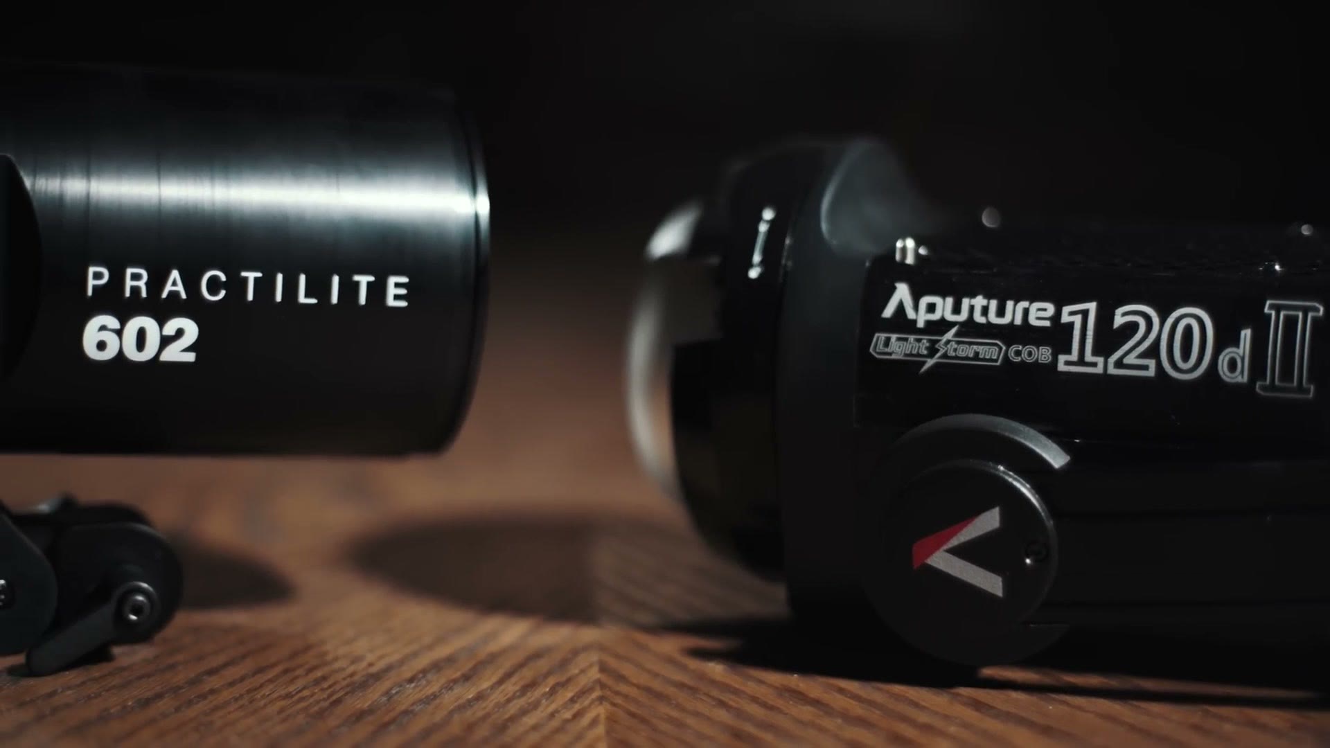 A Practilite 602 and an Aputure 120d II standing side by side on a wooden table.