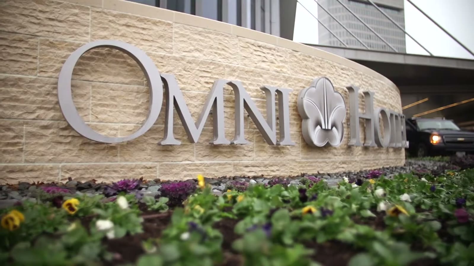 Close-up of the Omni Hotel stone signage in downtown Dallas with a purple flower bed below