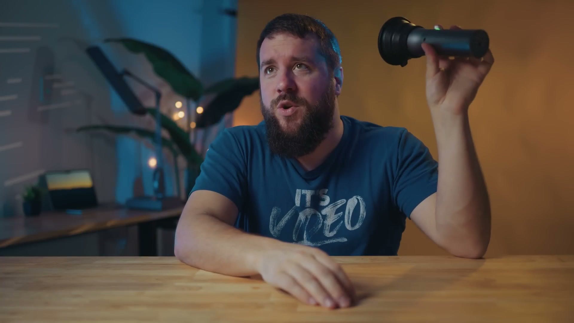 Matt holding up the SmallRig RF 10C, a small cylindrical light that looks like a flashlight, casting blue light across the room