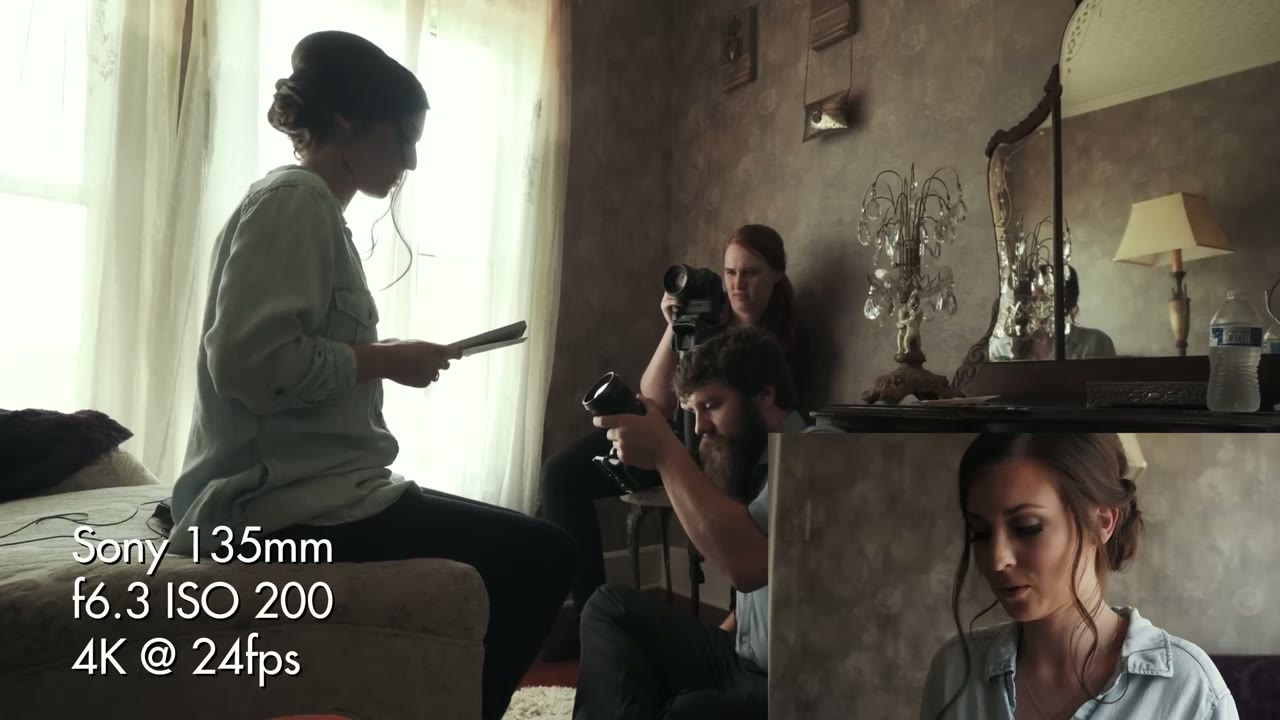 Overlay reads Sony 135mm f6.3 ISO 200 4K @ 24fps as the bride sits on an ottoman reading a letter while two shooters film her