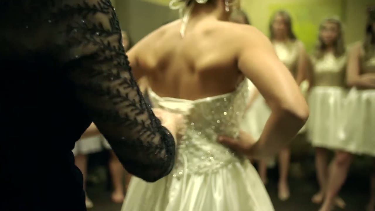 Bridesmaid in a black lace sleeve lacing up the back of the bride's beaded corset gown