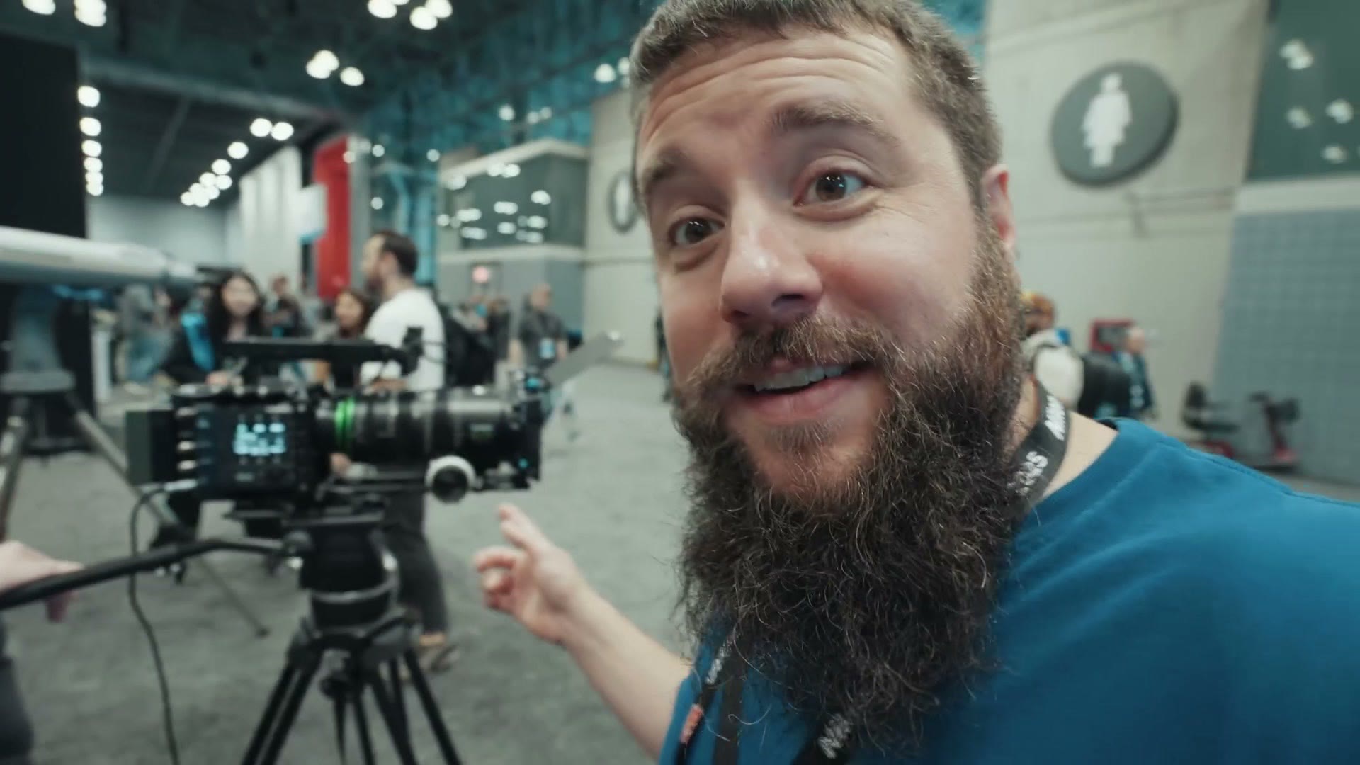 Matt pointing back at a Fujifilm GFX Eterna cinema camera set up on a tripod on the expo floor