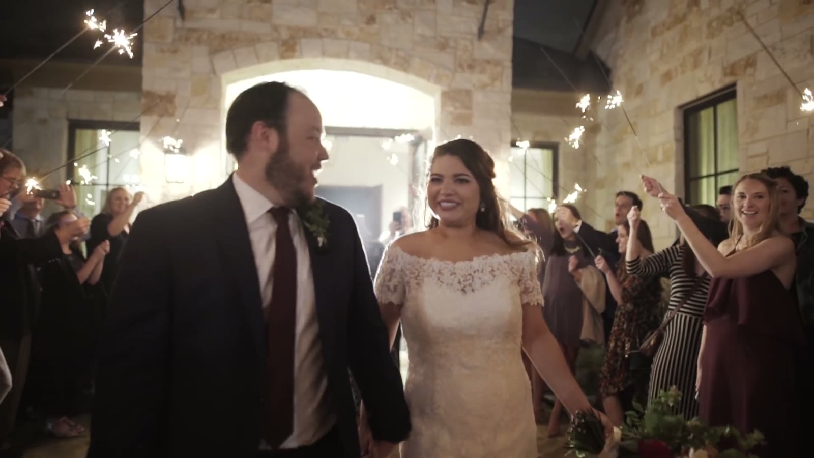 The couple leaving through a sparkler exit surrounded by guests