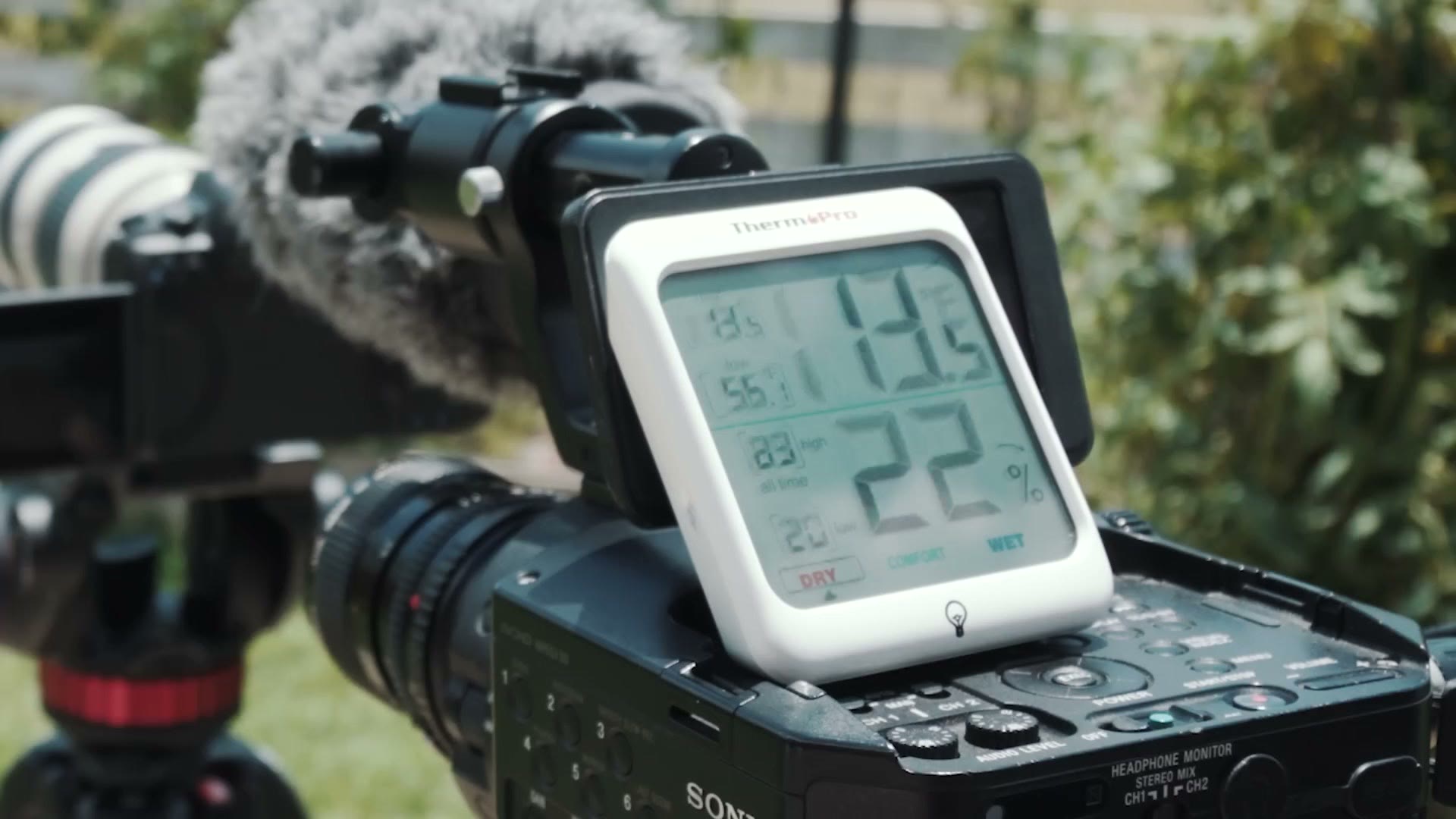 A digital thermometer resting on the camera rig outdoors reading 113 degrees Fahrenheit and 22 percent humidity