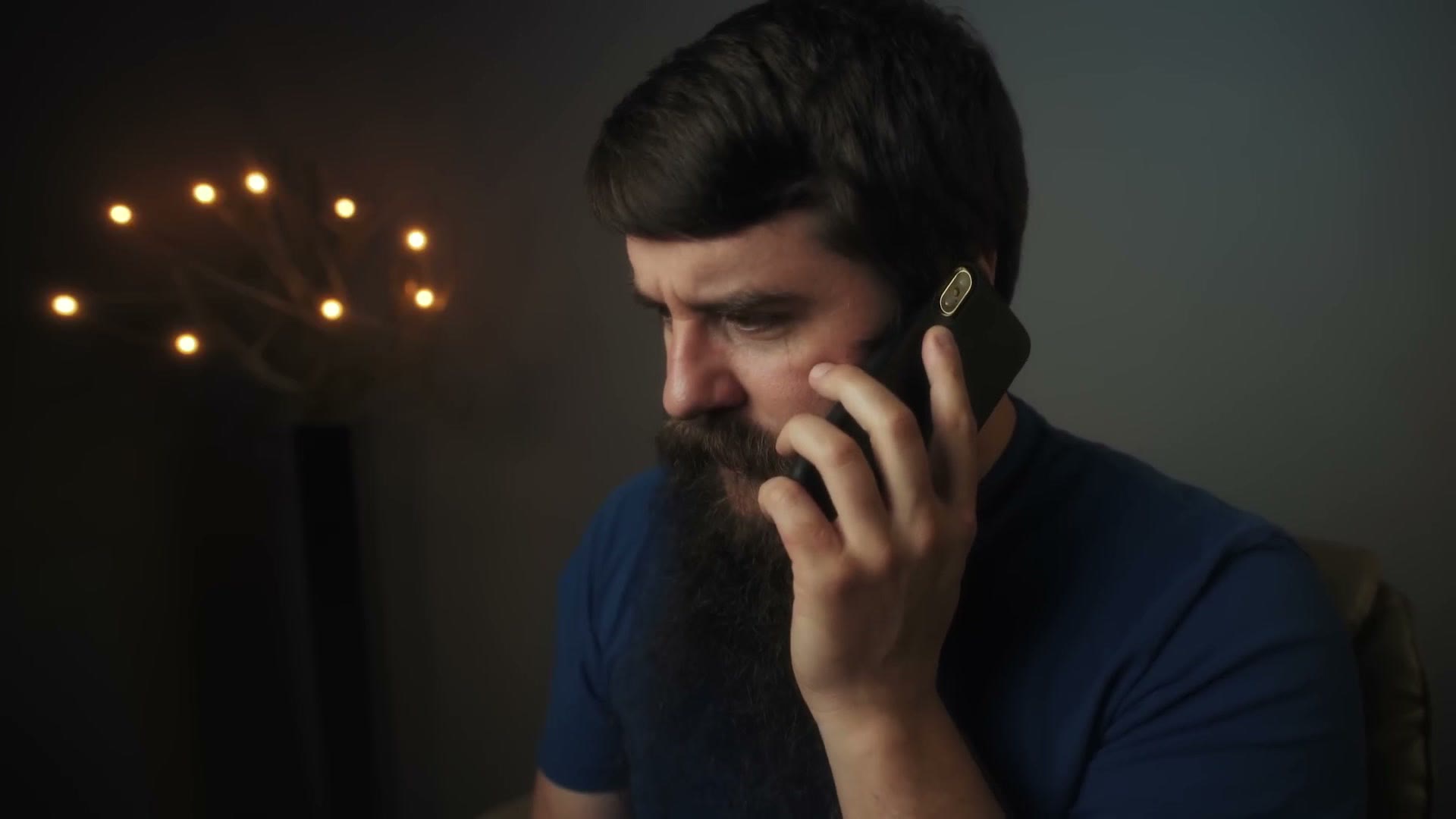 Matt sitting in his studio holding a phone to his ear with a pained expression, mid-conversation.