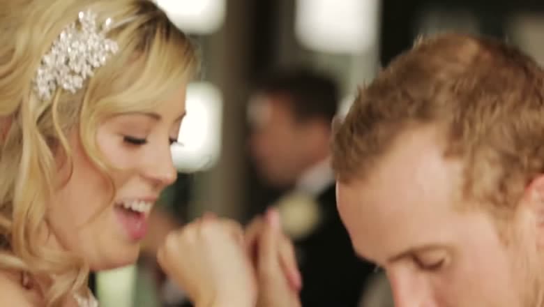 The bride and groom close together on the dance floor at the reception, both laughing