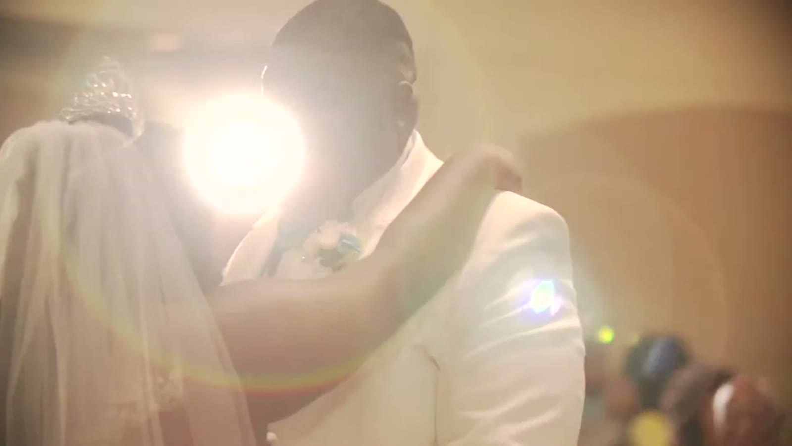 Bride and groom in a close embrace, backlit by warm golden light during the reception