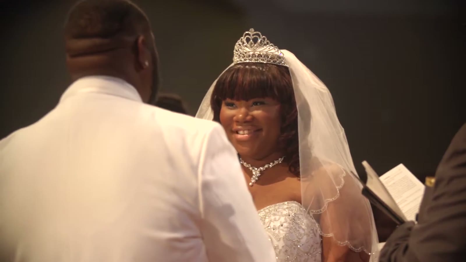 Close-up of the bride in her tiara and veil smiling at the groom during the ceremony