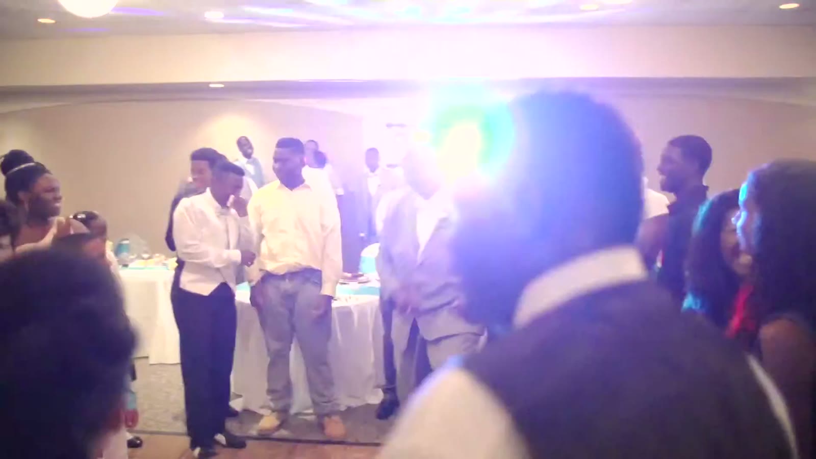 Groomsmen and guests dancing on the reception floor under colorful lights