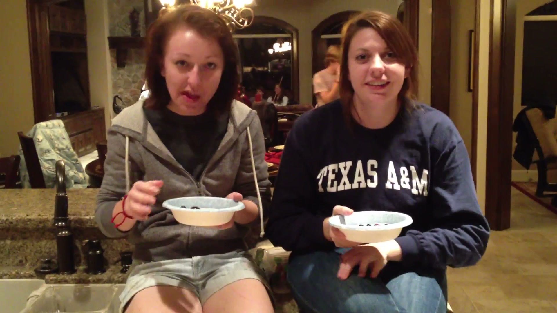 The two competitors looking at the camera with their cheeks full, holding their bowls, at the end of the round
