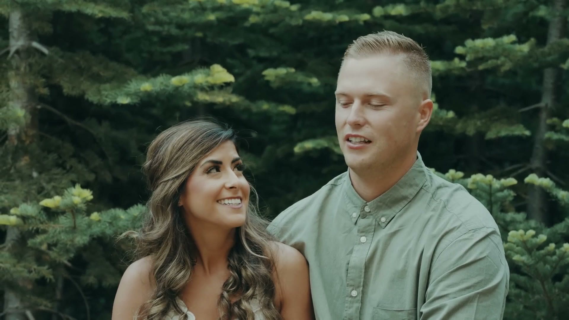The couple being interviewed sitting on a log in the forest
