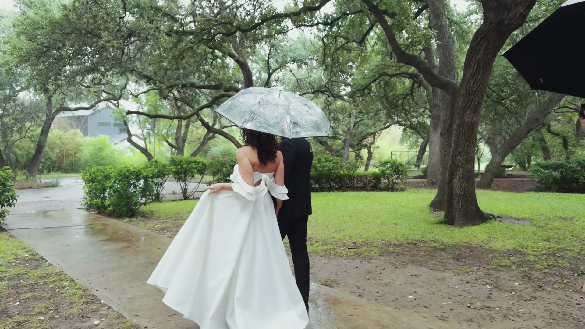 The couple together under an umbrella in the rain outside the venue