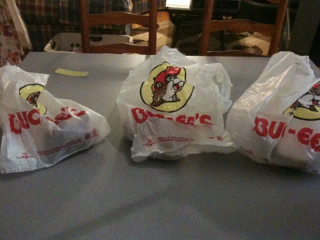 Three white plastic Buc-ee's carrier bags printed with the cartoon beaver logo, sitting on a plastic covered table