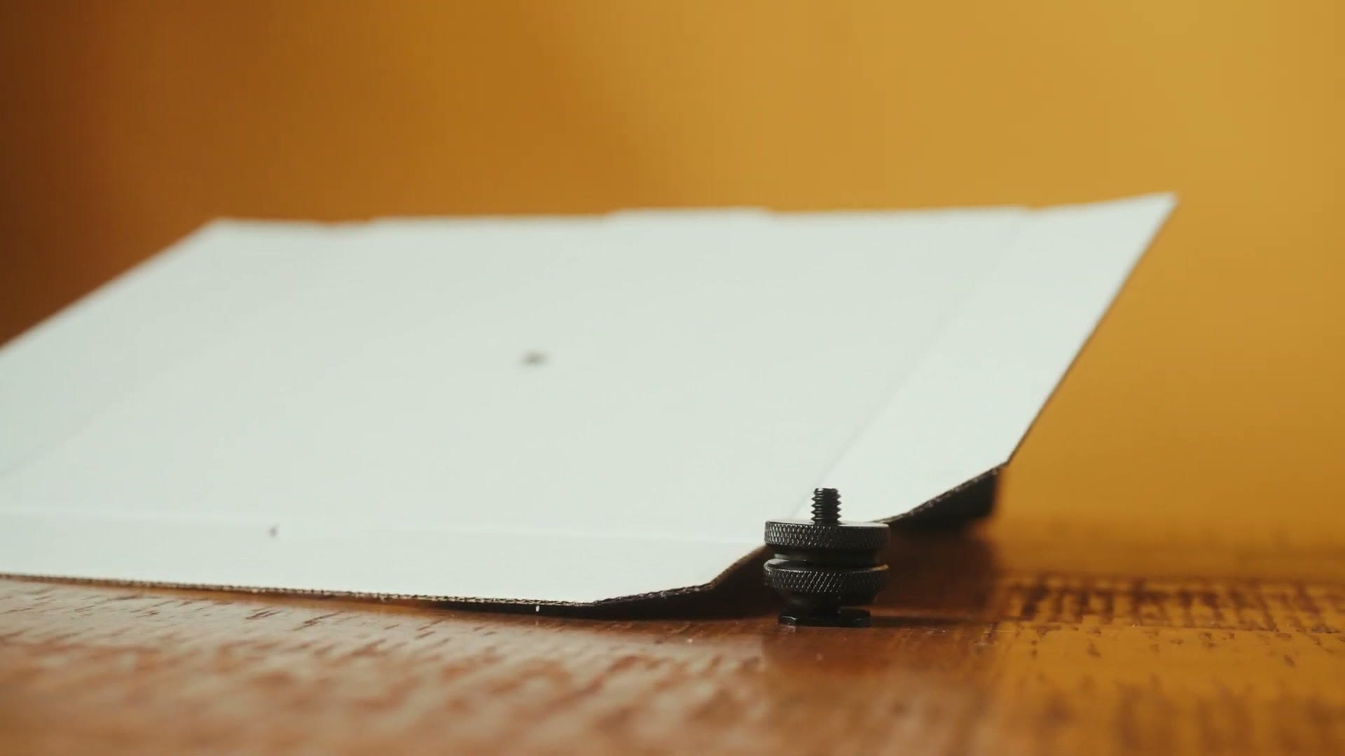 A piece of white foam board with a hot shoe screw pushed through it