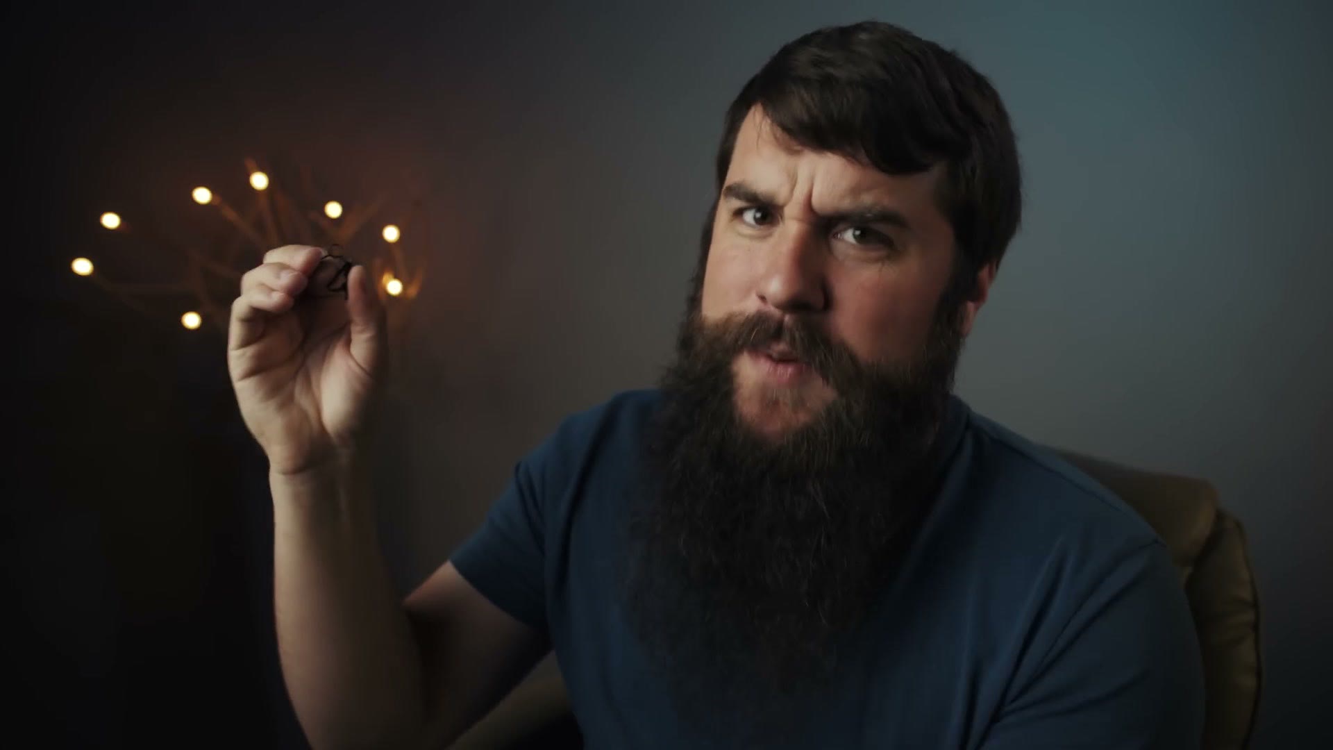 Matt holding a tiny black metal lavalier microphone lapel clip between two fingers.