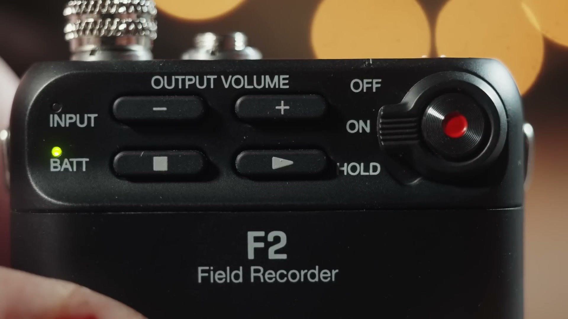 Close-up of the top of a Zoom F2 showing the recessed OFF, ON and HOLD switch beside the red record button.