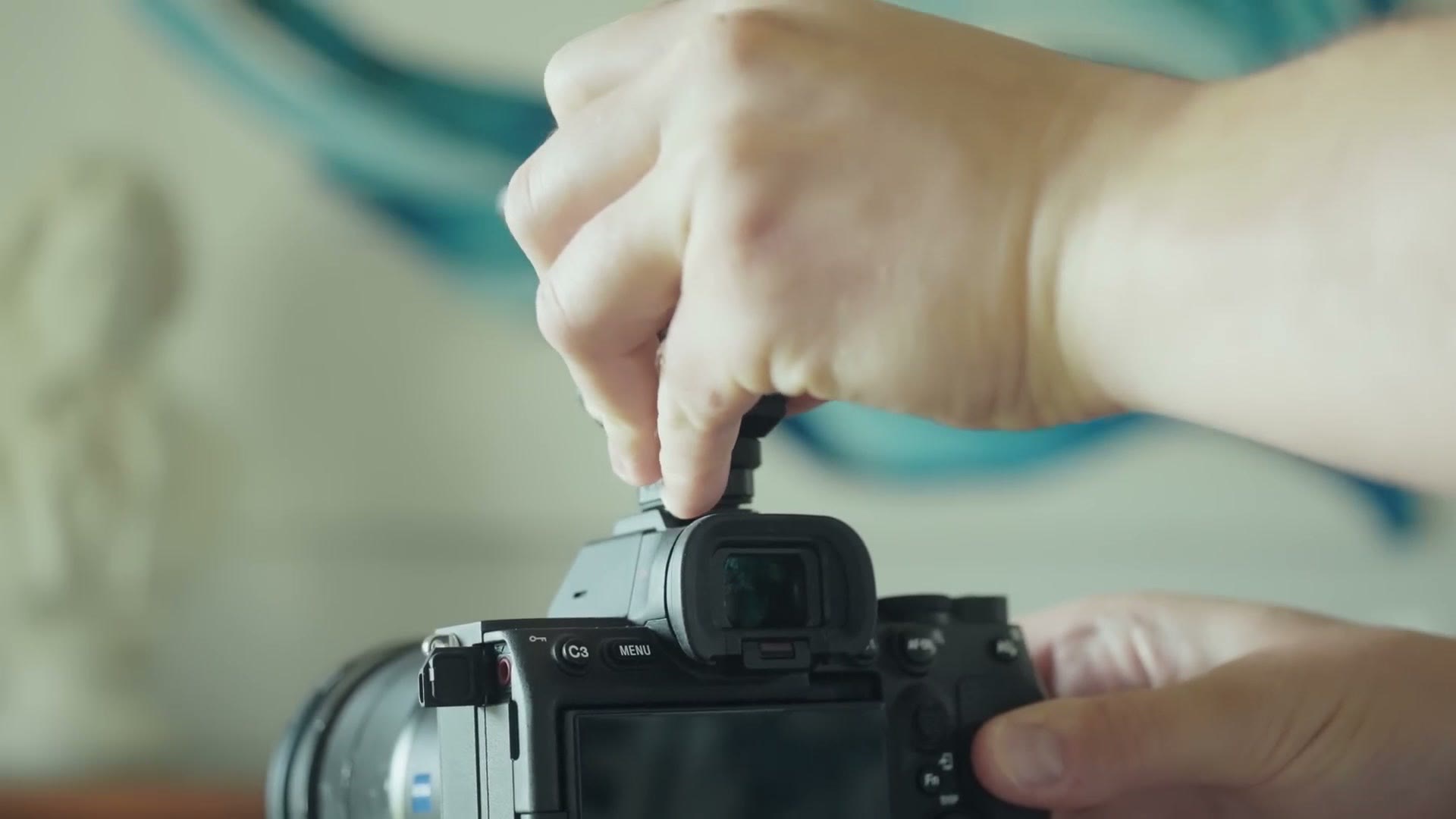 Hand sliding the Sony ECM-G1 into the Multi Interface hot shoe of a Sony camera