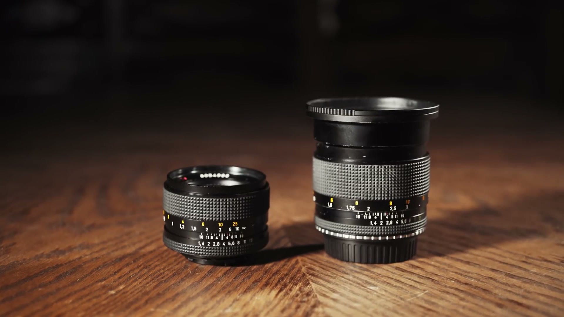 The Contax Zeiss 50mm and 85mm lenses standing side by side on a table, the 85mm noticeably larger