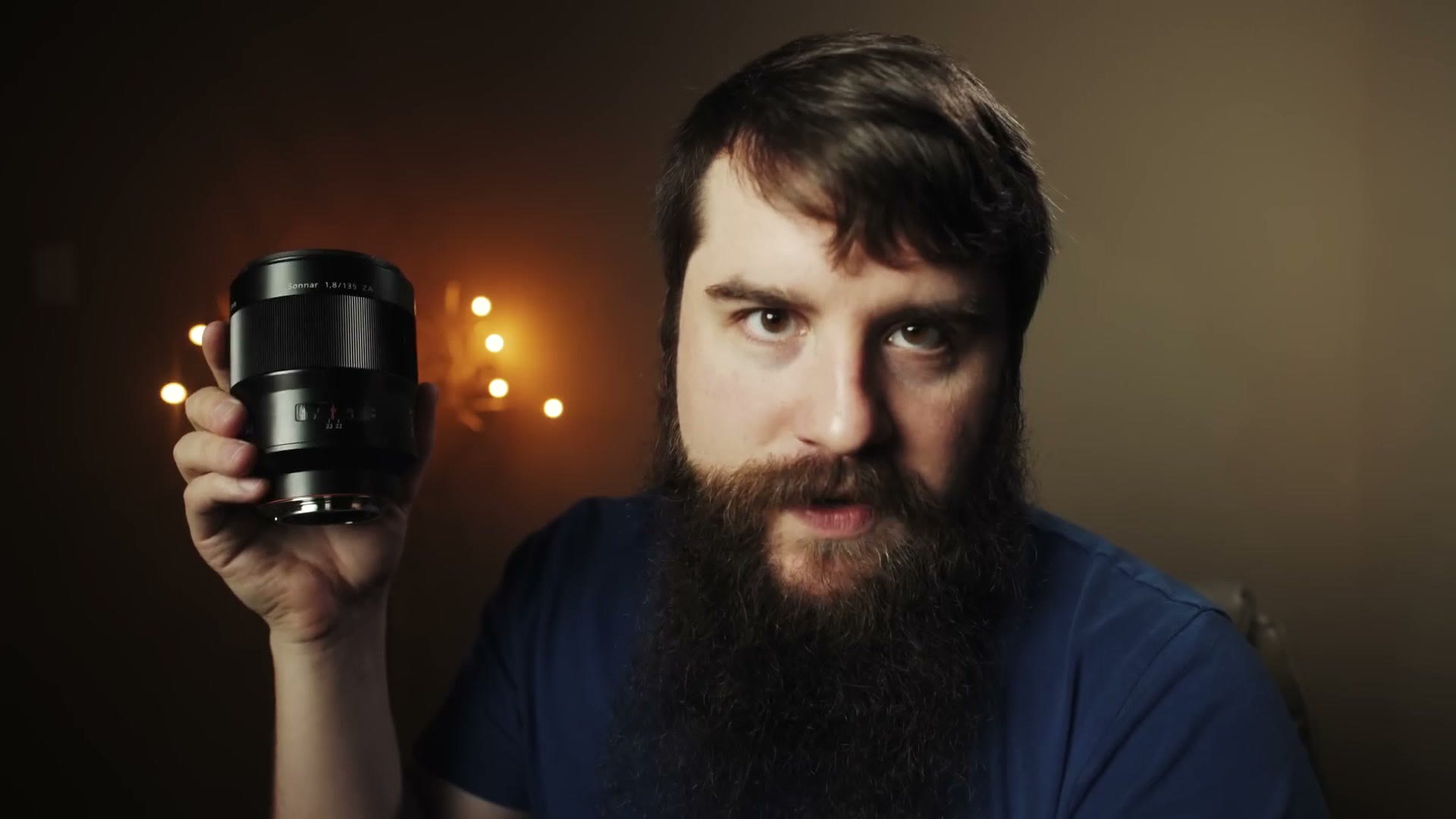 Matt holding up a Sony Zeiss 135mm f1.8 lens beside his head