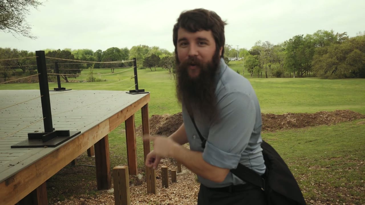Matt pointing toward string-light posts on the wooden reception deck while explaining where to find power