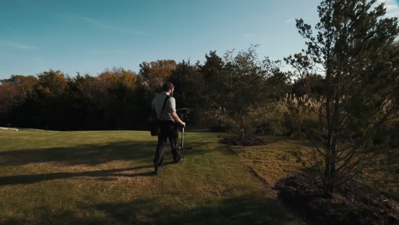 Walking the venue lawn with a camera and monopod, scouting the two trees where the groom will stand for the first look