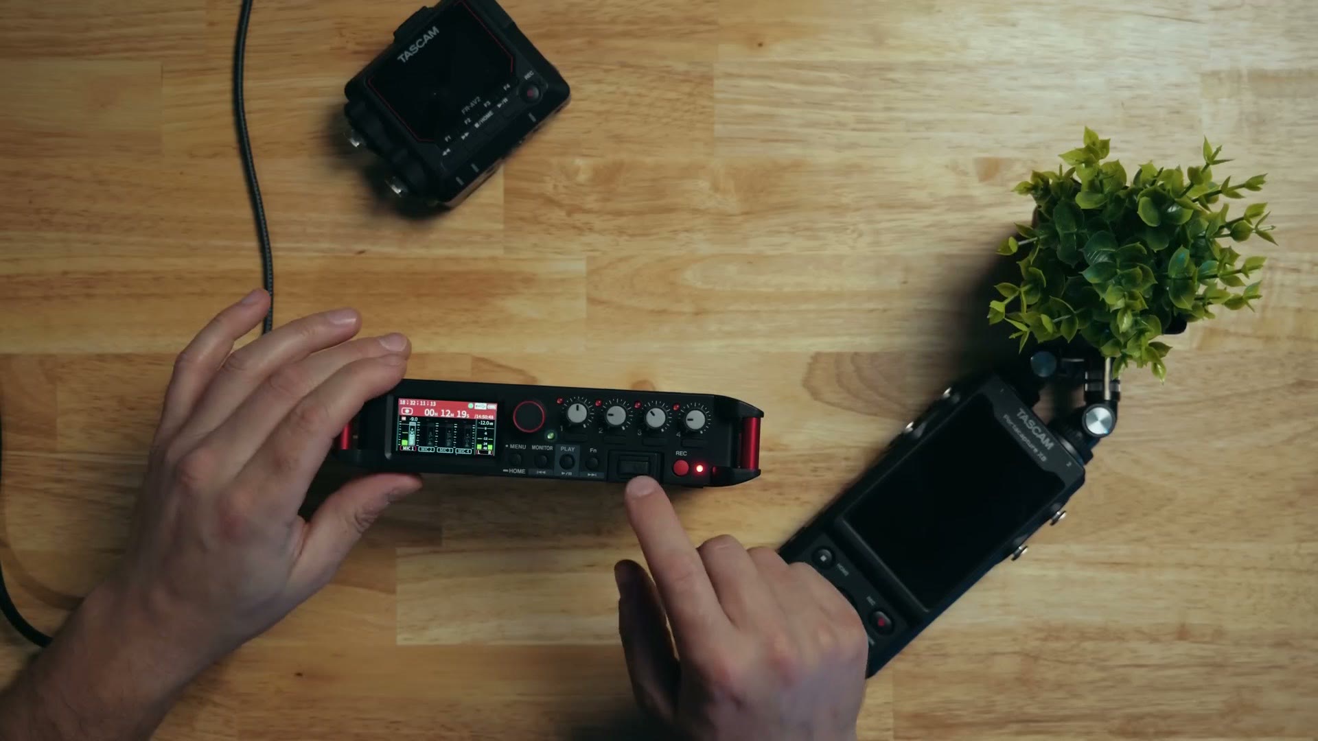 Top down view of the Tascam FR-AV4 control face showing its small screen, four gain dials and transport buttons