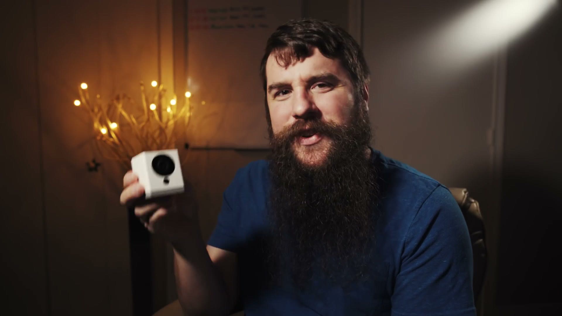 Matt holding a small white Wyze Cam security camera up to the camera