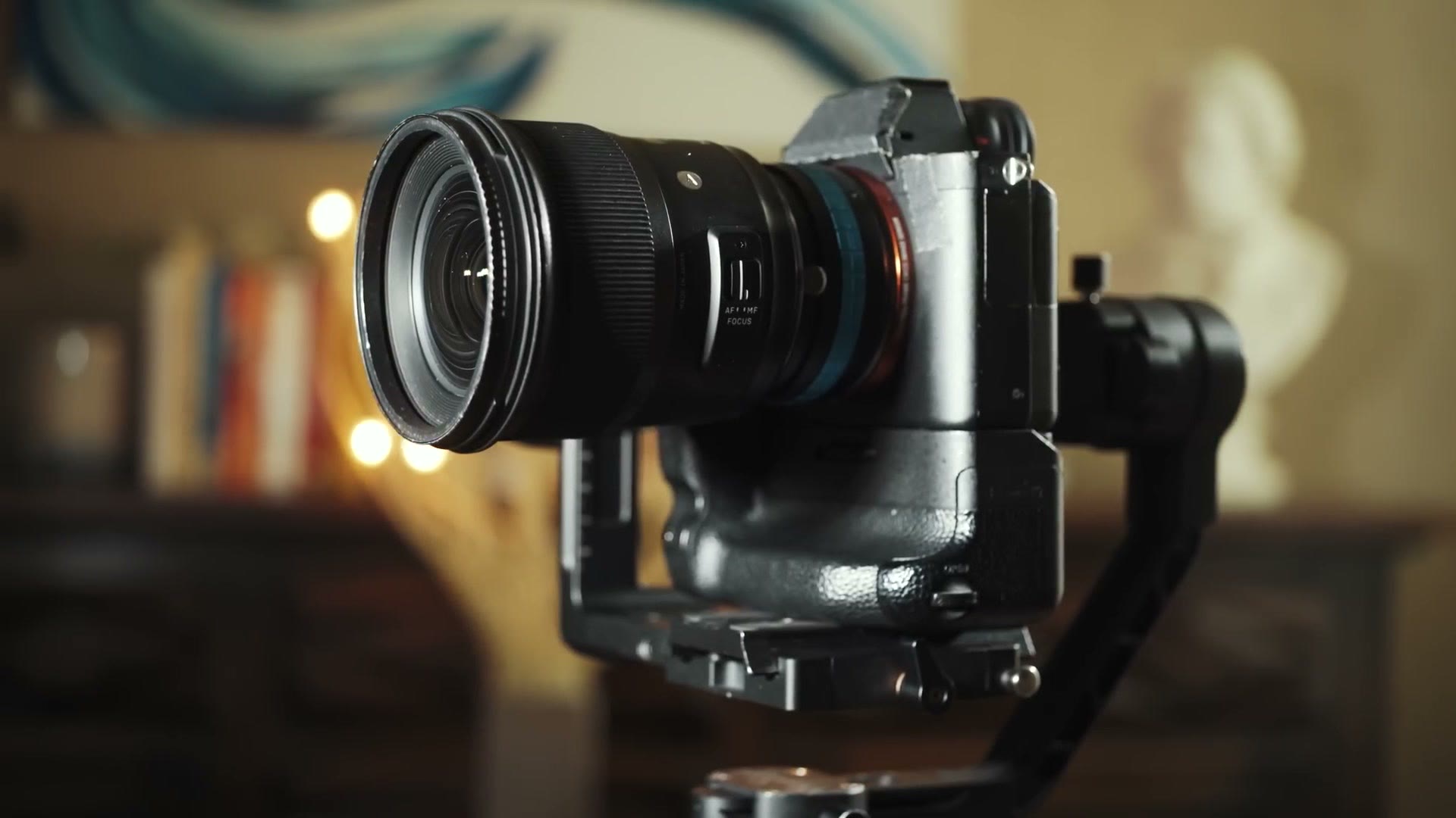 A Sony mirrorless camera with an adapted Sigma 24mm lens balanced on a three axis gimbal