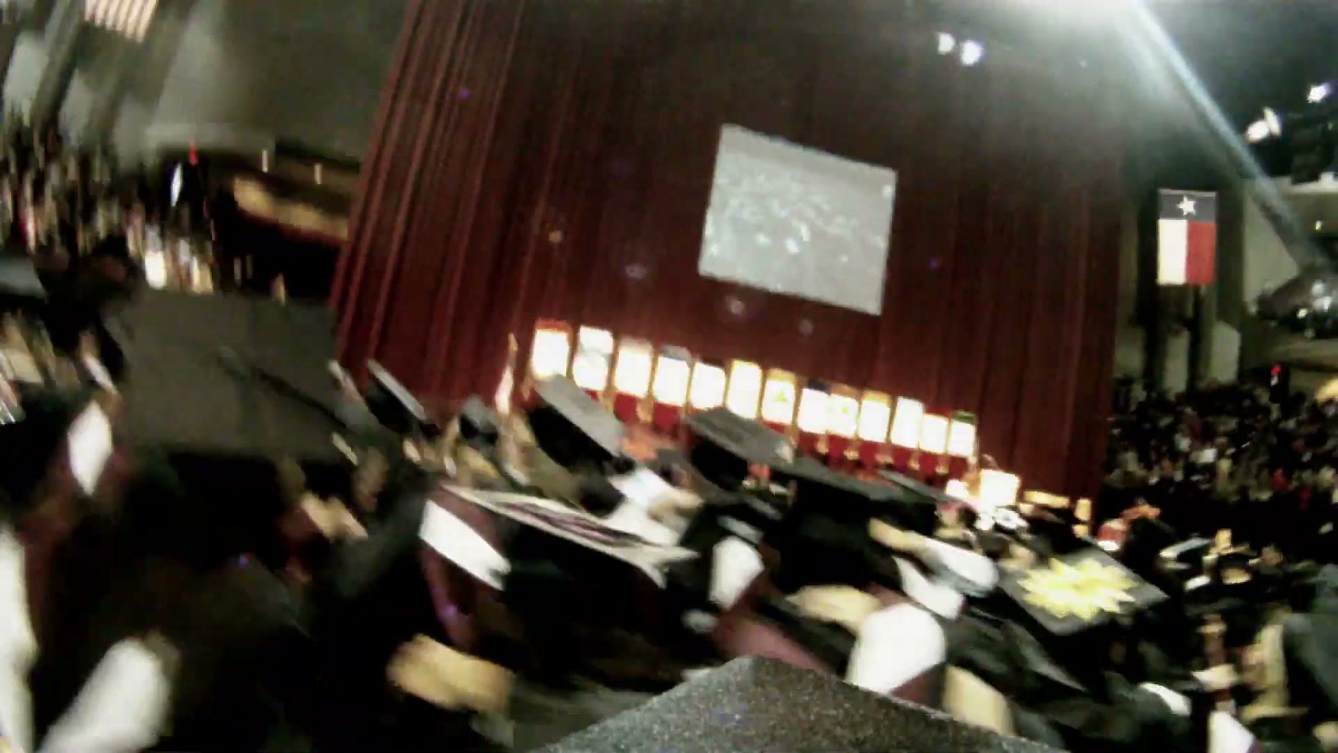 A motion blurred view of the auditorium spinning as the graduation cap is thrown into the air with the camera still attached
